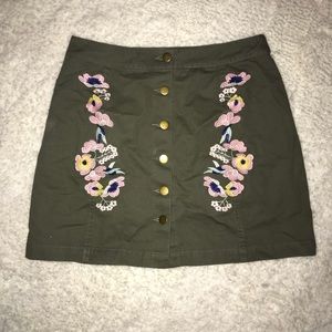 Army green mini skirt with floral embroidery.